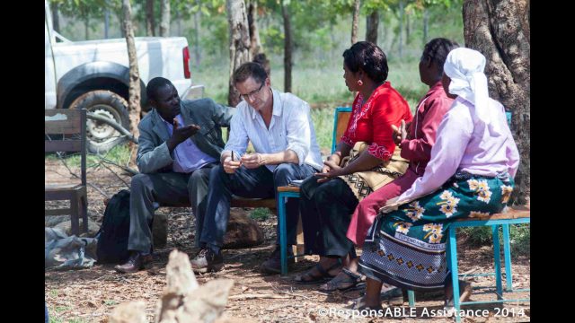 A small group sit and talk to us while a Community Worker translates what they are saying
