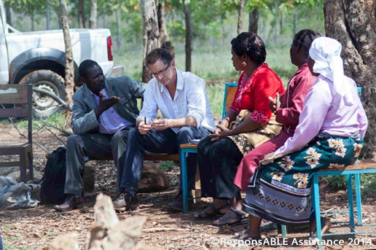 A small group sit and talk to us while a Community Worker translates what they are saying