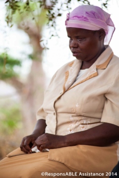 A blind lady sits quietly with her hands in her lap