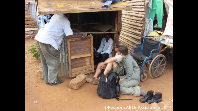 Margaret, a single Mum, supports her 2 children by running her business from this roadside shack. Margaret’s manual wheelchair sits outside her small, low shack while representatives from ResponsABLE Assistance meet and talk with her