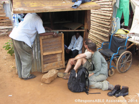 Margaret, a single Mum, supports her 2 children by running her business from this roadside shack. Margaret’s manual wheelchair sits outside her small, low shack while representatives from ResponsABLE Assistance meet and talk with her