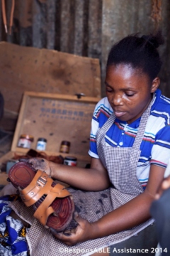 Margaret holds a sandal she has just cleaned for its owner