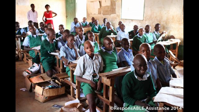 A classroom where three students have to sit closely together on each small and narrow bench table
